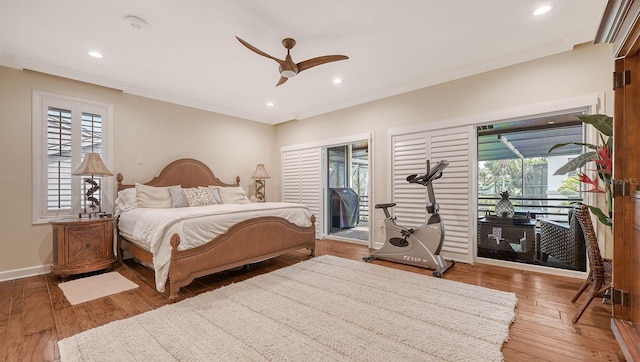 bedroom with multiple windows, wood-type flooring, access to outside, and ceiling fan