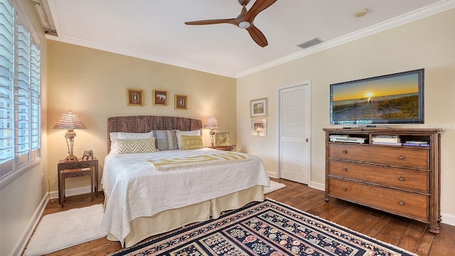 bedroom with dark wood-type flooring, ceiling fan, ornamental molding, and a closet