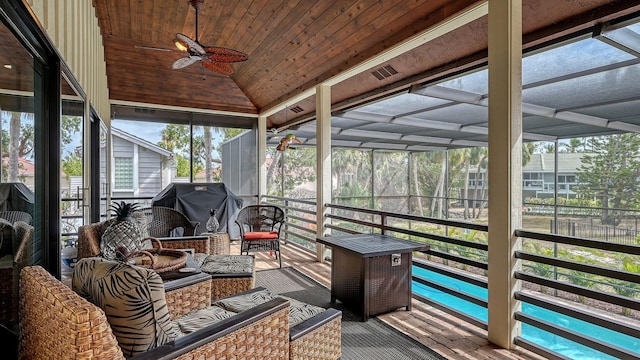 sunroom featuring lofted ceiling, wooden ceiling, and ceiling fan