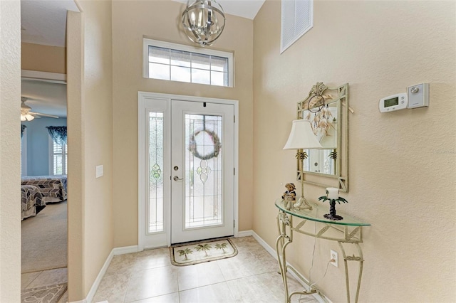 foyer featuring light tile patterned flooring, an inviting chandelier, and a wealth of natural light