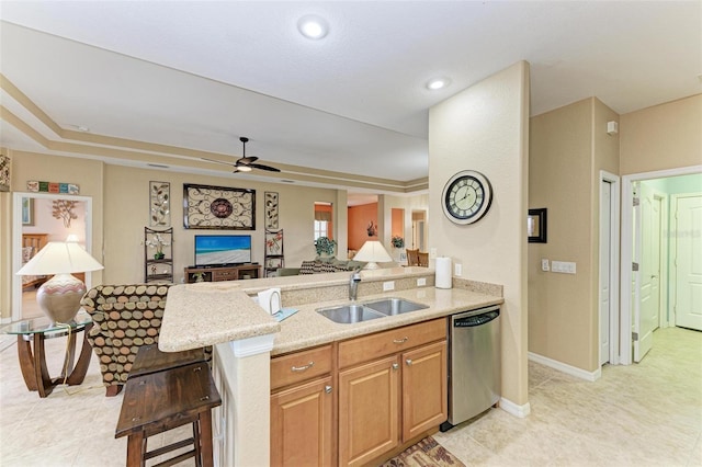 kitchen with dishwasher, ceiling fan, sink, light stone counters, and a breakfast bar