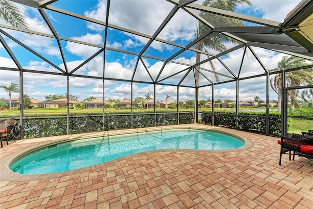 view of swimming pool featuring a patio, glass enclosure, and a water view