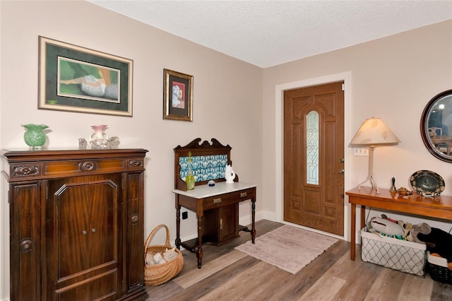 foyer with light wood-type flooring and a textured ceiling