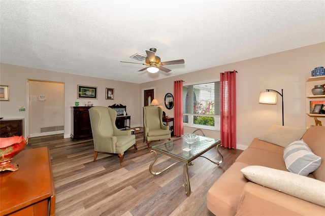 living room featuring hardwood / wood-style floors, a textured ceiling, and ceiling fan