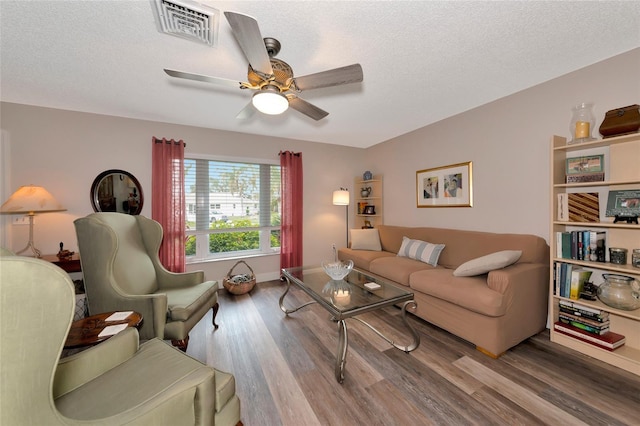 living room featuring ceiling fan, hardwood / wood-style floors, and a textured ceiling