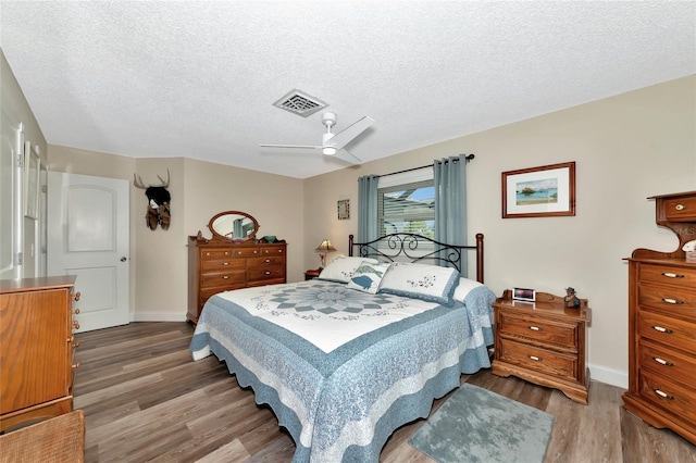 bedroom with hardwood / wood-style flooring, a textured ceiling, and ceiling fan