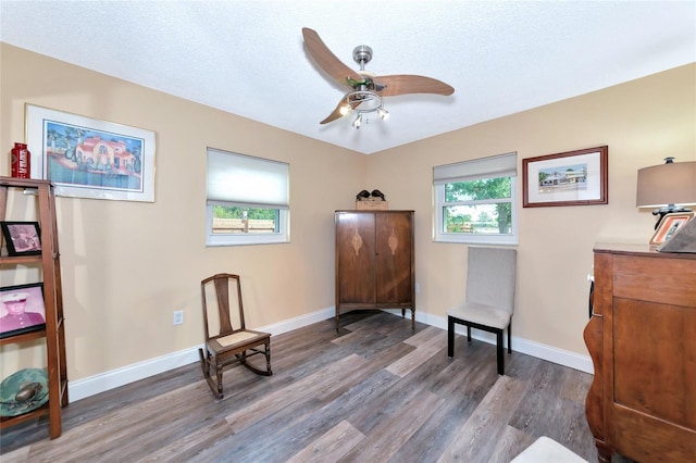 living area with ceiling fan, dark hardwood / wood-style floors, and a textured ceiling