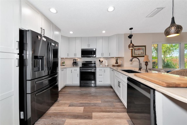 kitchen with pendant lighting, white cabinetry, appliances with stainless steel finishes, and sink