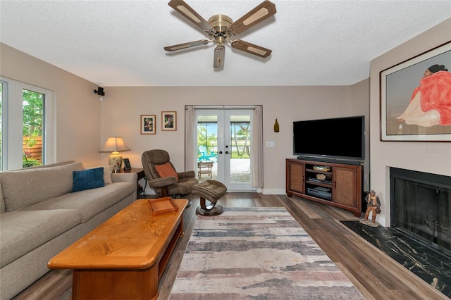 living room featuring ceiling fan, french doors, dark wood-type flooring, and a textured ceiling