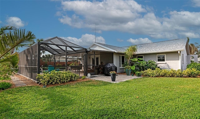 rear view of house featuring glass enclosure, a patio area, and a lawn