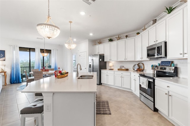 kitchen featuring sink, hanging light fixtures, stainless steel appliances, and an island with sink