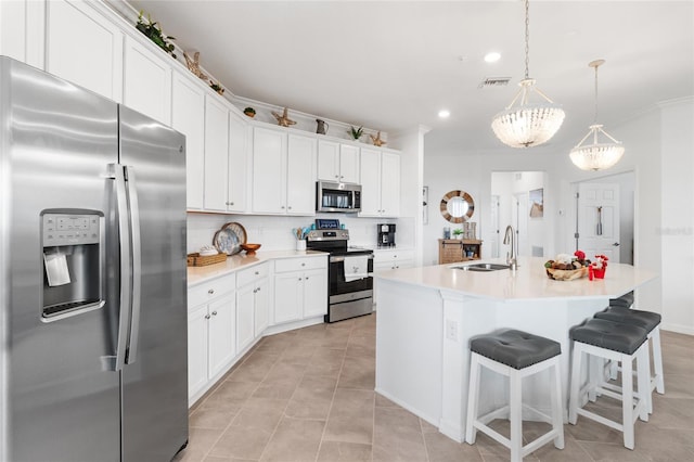 kitchen with pendant lighting, white cabinetry, stainless steel appliances, sink, and a center island with sink