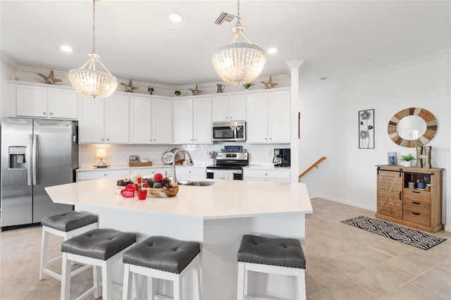 kitchen with ornamental molding, a center island with sink, white cabinets, and appliances with stainless steel finishes