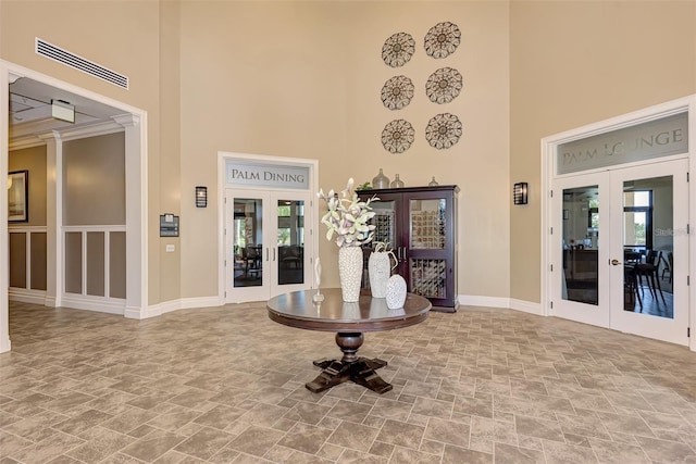 foyer featuring ornamental molding, a high ceiling, and french doors