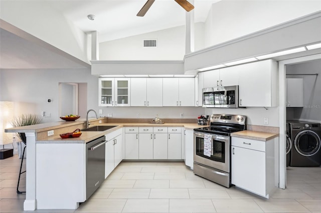 kitchen featuring a kitchen bar, sink, white cabinetry, kitchen peninsula, and stainless steel appliances