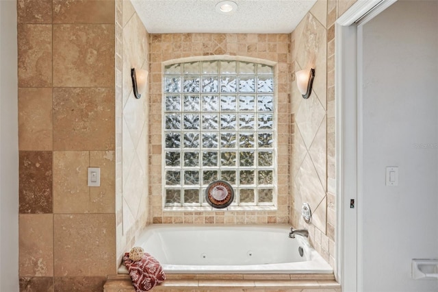 bathroom with a relaxing tiled tub, a textured ceiling, and tile walls