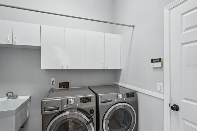 clothes washing area featuring cabinets, sink, and independent washer and dryer