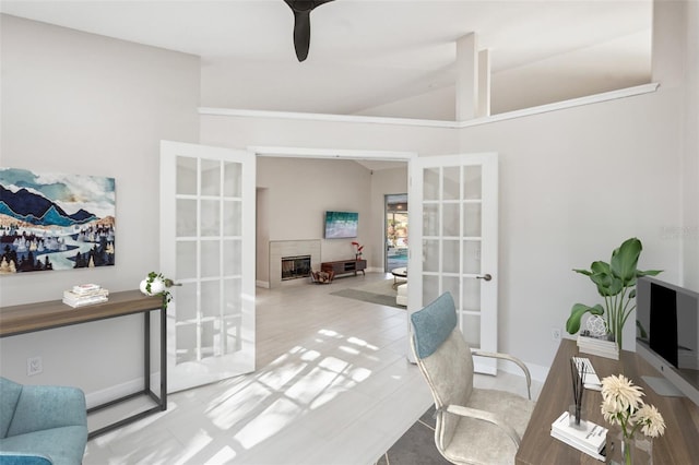 office space featuring a tiled fireplace, vaulted ceiling, and french doors