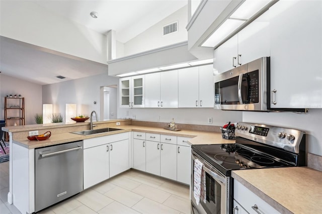 kitchen featuring sink, white cabinetry, vaulted ceiling, appliances with stainless steel finishes, and kitchen peninsula