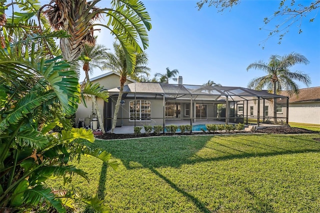 rear view of property featuring a lanai and a yard