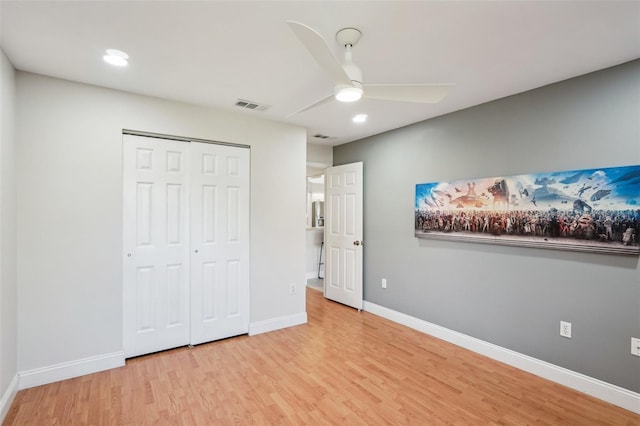 unfurnished bedroom with ceiling fan, light wood-type flooring, and a closet