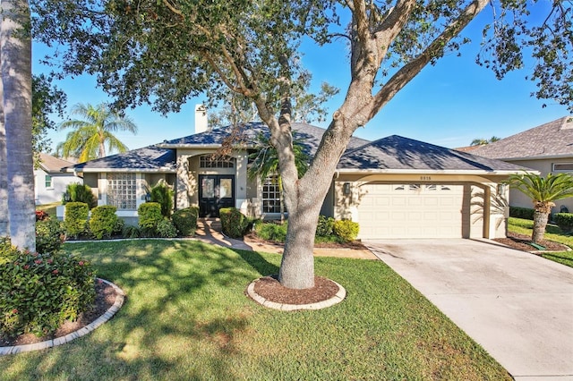 single story home with a garage, a front yard, and french doors