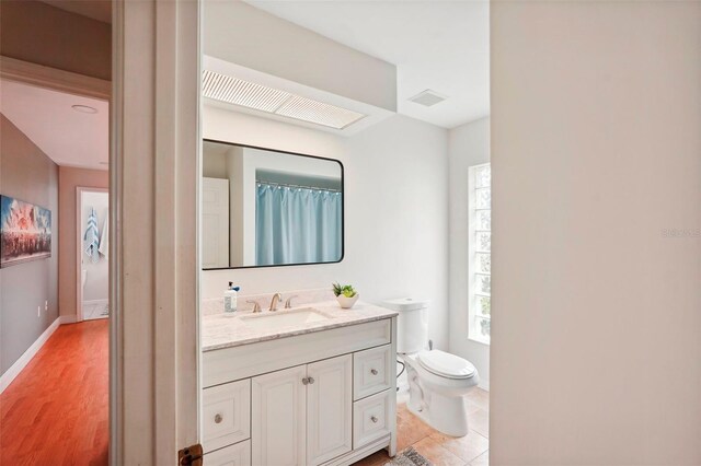 bathroom featuring toilet, vanity, and baseboards