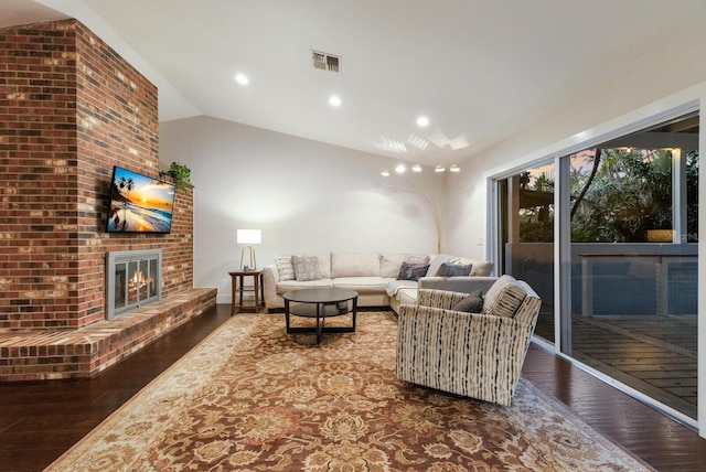 living room featuring hardwood / wood-style flooring, a brick fireplace, and lofted ceiling