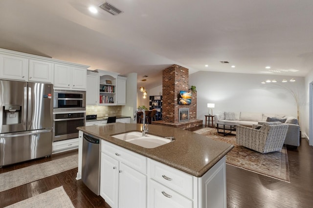 kitchen with sink, white cabinetry, appliances with stainless steel finishes, and lofted ceiling