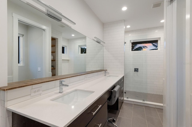 bathroom featuring backsplash, tile patterned floors, vanity, and a tile shower