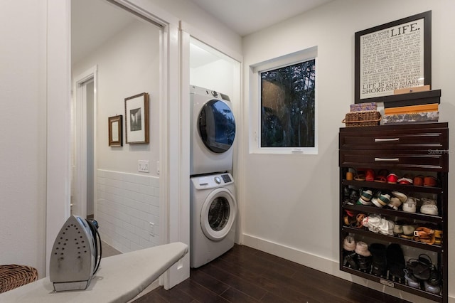 laundry room featuring stacked washer / drying machine and dark hardwood / wood-style flooring