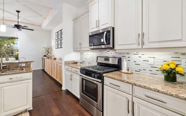 kitchen featuring stainless steel appliances, dark wood-type flooring, light stone countertops, white cabinets, and sink