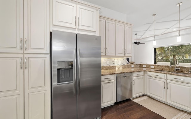 kitchen with pendant lighting, appliances with stainless steel finishes, dark stone countertops, decorative backsplash, and sink