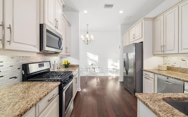 kitchen featuring pendant lighting, dark wood-type flooring, white cabinetry, stainless steel appliances, and light stone counters