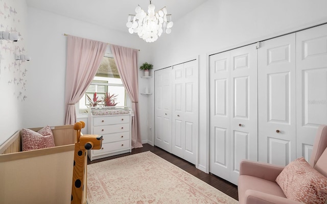 bedroom with two closets, dark hardwood / wood-style floors, and an inviting chandelier