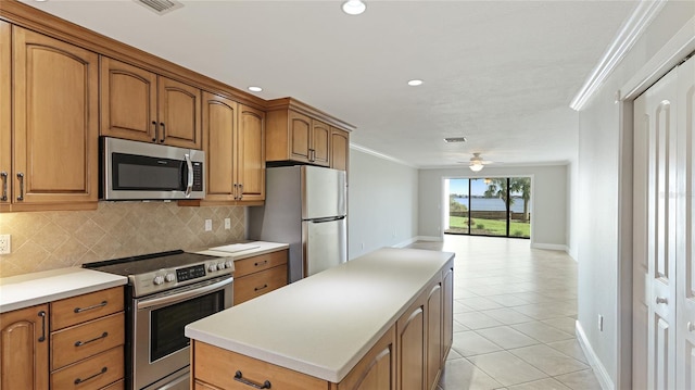 kitchen with light tile patterned flooring, a center island, ornamental molding, stainless steel appliances, and decorative backsplash