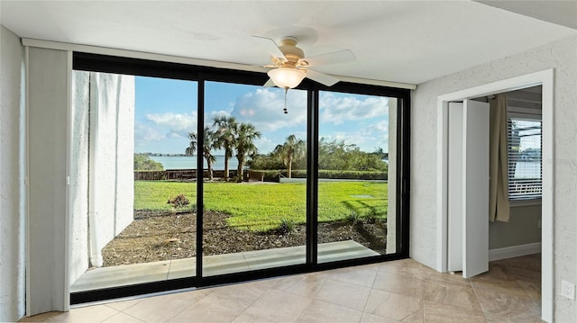 doorway to outside with a water view, ceiling fan, a healthy amount of sunlight, and light tile patterned flooring