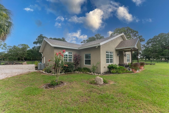 view of side of property featuring a yard and central AC