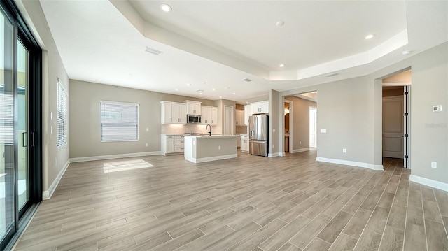 unfurnished living room with sink and a tray ceiling