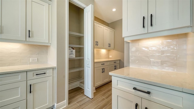 kitchen featuring light stone counters, decorative backsplash, and white cabinets