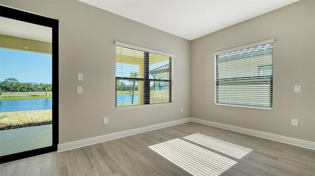 spare room with light hardwood / wood-style flooring and a water view