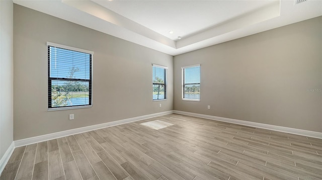 spare room featuring light hardwood / wood-style floors and a raised ceiling