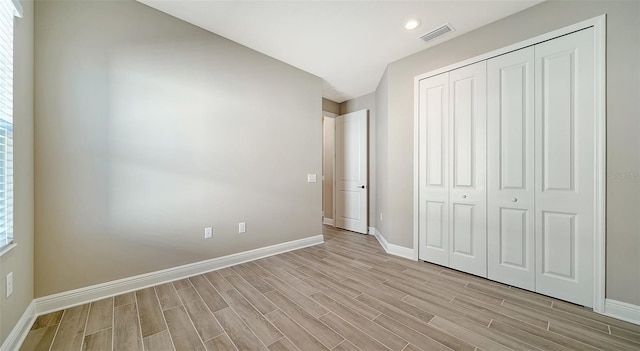 unfurnished bedroom with multiple windows, a closet, and light hardwood / wood-style flooring