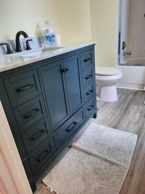 full bathroom featuring toilet, vanity, tiled shower / bath combo, and hardwood / wood-style flooring