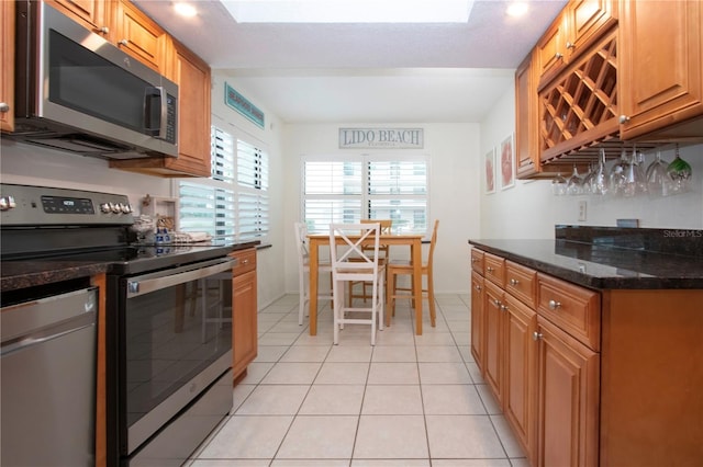 kitchen with stainless steel appliances, dark stone countertops, and light tile patterned floors