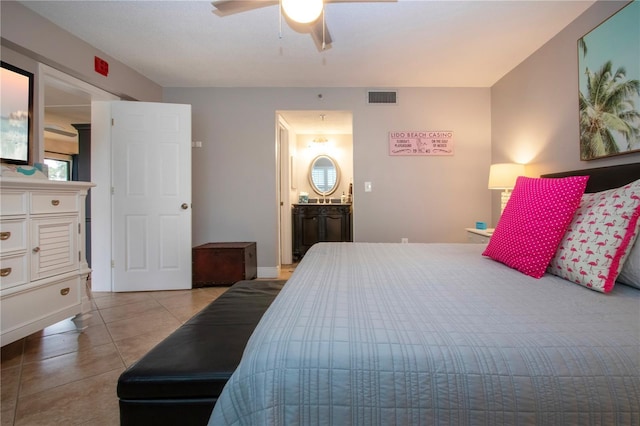 bedroom with connected bathroom, light tile patterned floors, and ceiling fan