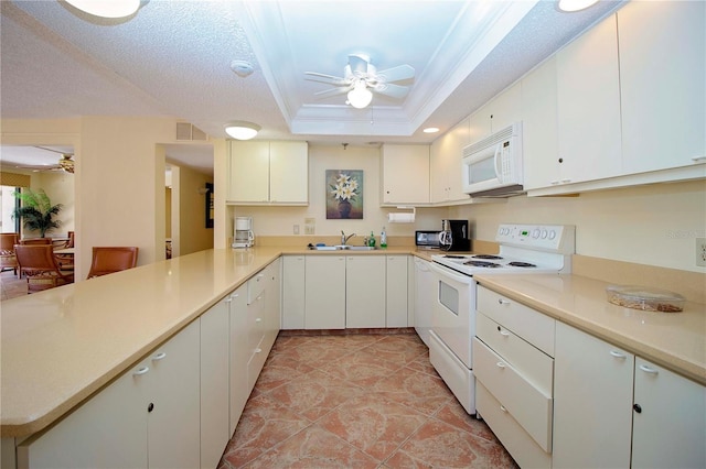 kitchen with a raised ceiling, white cabinets, white appliances, and kitchen peninsula