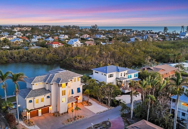 aerial view at dusk featuring a water view