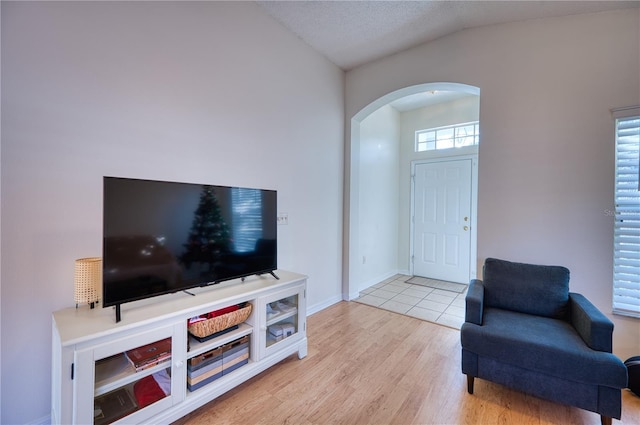 interior space with vaulted ceiling, a textured ceiling, and light wood-type flooring