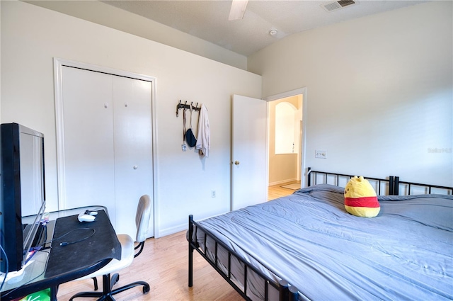 bedroom featuring lofted ceiling, a closet, ceiling fan, and light wood-type flooring